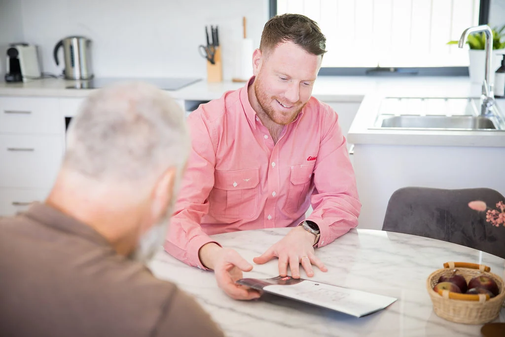 Tommie Watts discussing property with a client at a kitchen bench.