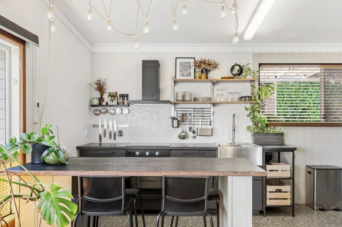 A light and neatly presented kitchen with pendant lights and a clear island.